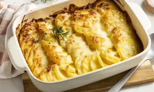 Ein goldbrauner Kartoffelauflauf mit geschmolzenem Käse, garniert mit Rosmarin. Perfekt für ein Kartoffelgratin Rezept.
