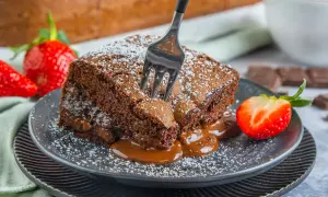 Ein Stück saftiger Schokoladenkuchen, bestäubt mit Puderzucker, mit flüssiger Schokolade, die herausläuft. Ein perfektes brownies rezept saftig.