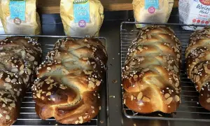 Frisch gebackene Hefezöpfe mit Mandelsplittern, bereit, um sie hefezopf frisch halten. Im Hintergrund Weizenmehl-Packungen.