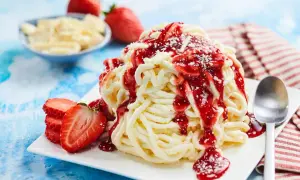 Ein köstliches Spaghetti-Eis-Dessert mit Erdbeersauce und frischen Erdbeeren, garniert mit weißer Schokolade.