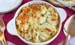 Ein goldbraun überbackener Blumenkohl Kartoffel Auflauf mit geschmolzenem Käse und frischen Kräutern, bereit zum Servieren.