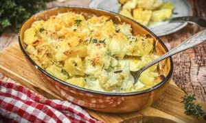 Herzhafter blumenkohl auflauf mit Kartoffeln und Käse überbacken, dampfend in einer Auflaufform.