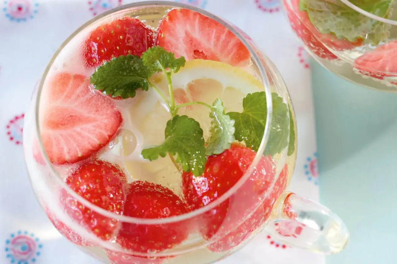 Erfrischendes Erdbeerbowle Rezept: Fruchtige Erdbeeren, Zitronenscheiben und Minze in einem Glas. Perfekt für heiße Tage!