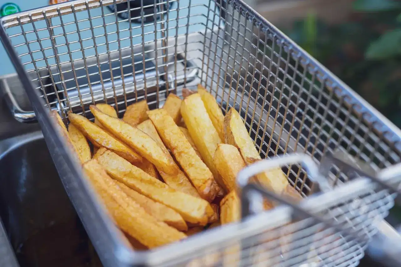 Goldbraune Pommes in einem Frittierkorb, bereit zum Genießen. So einfach ist es, Pommes selber machen!