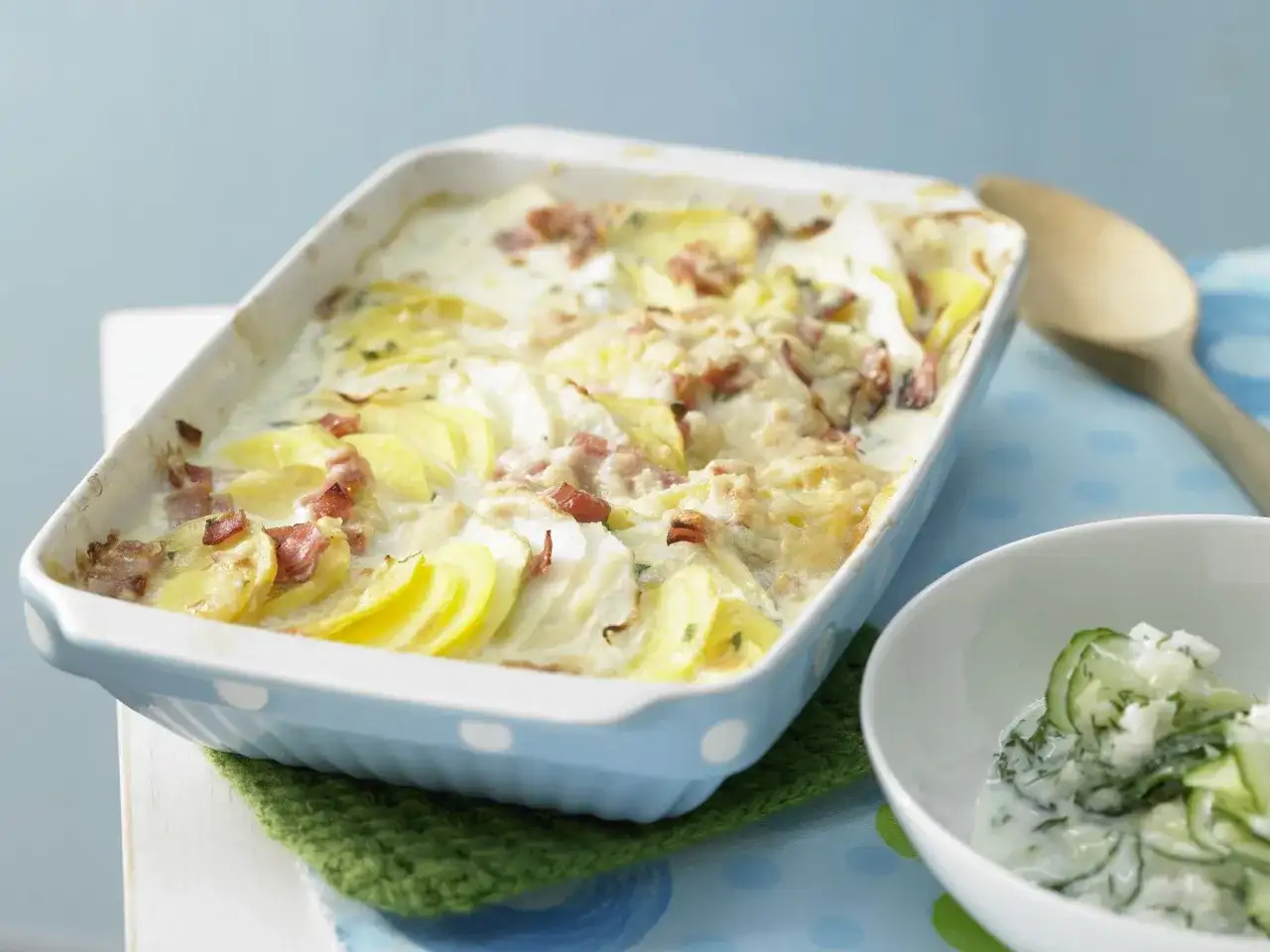 Herzhafte Kohlrabi-Rezepte: Kartoffel-Kohlrabi-Auflauf mit Speck und cremiger Sauce, dazu Gurkensalat.