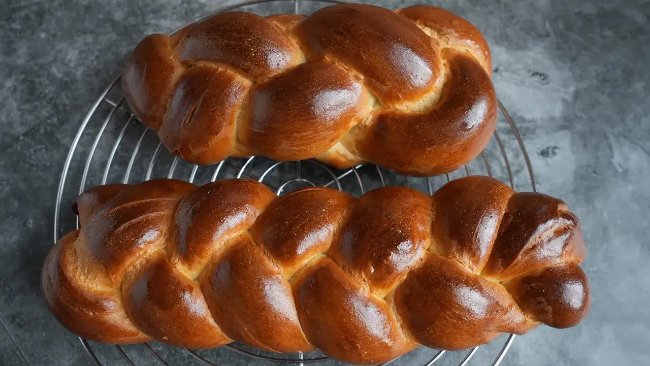 Zwei goldbraune Hefezöpfe auf einem Kuchengitter. Dieses Hefezopf Rezept ist perfekt für den Sonntagsbrunch.