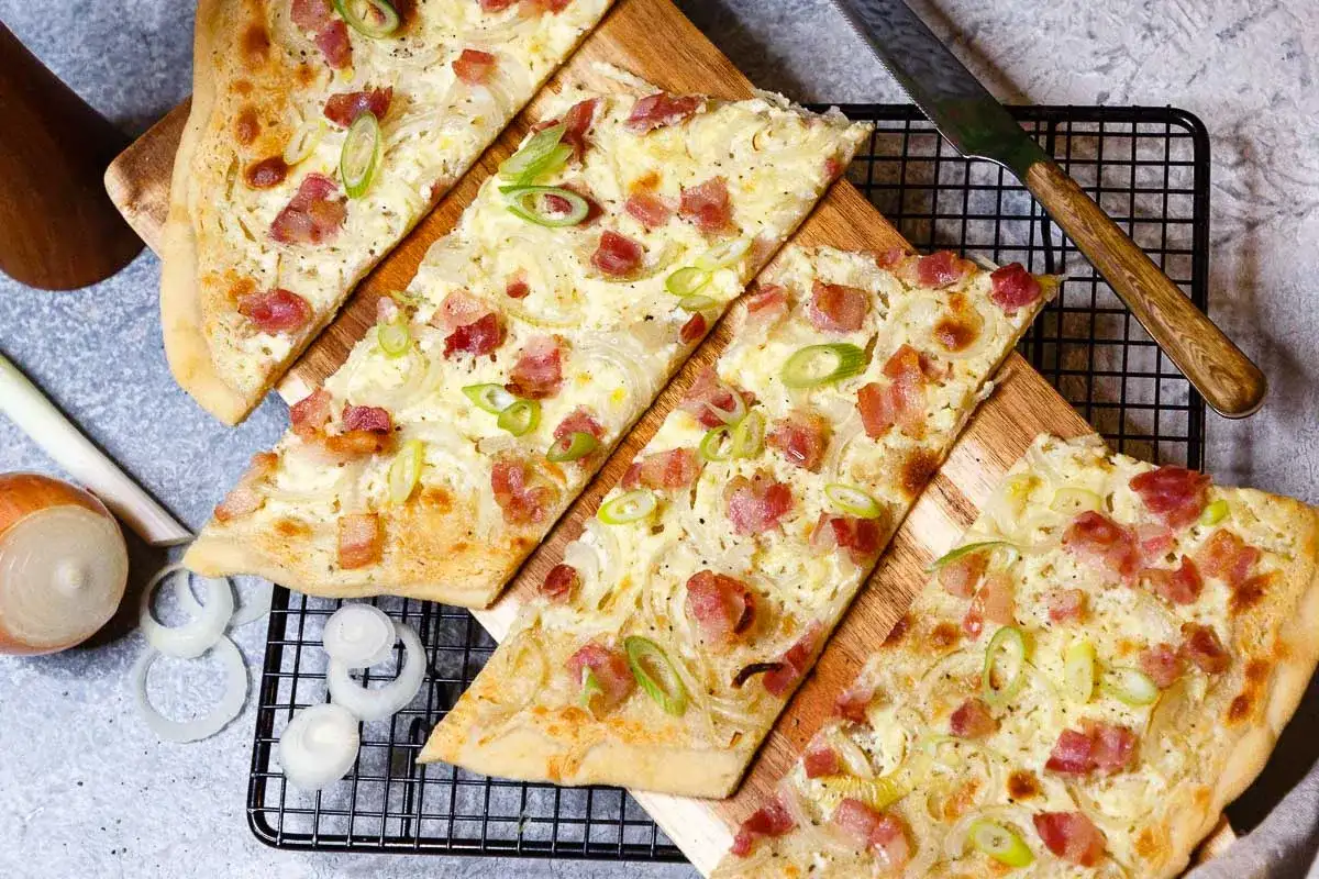 Drei knusprige Flammkuchen-Stücke mit Speck und Zwiebeln, bereit für ein köstliches Flammkuchen Rezept.