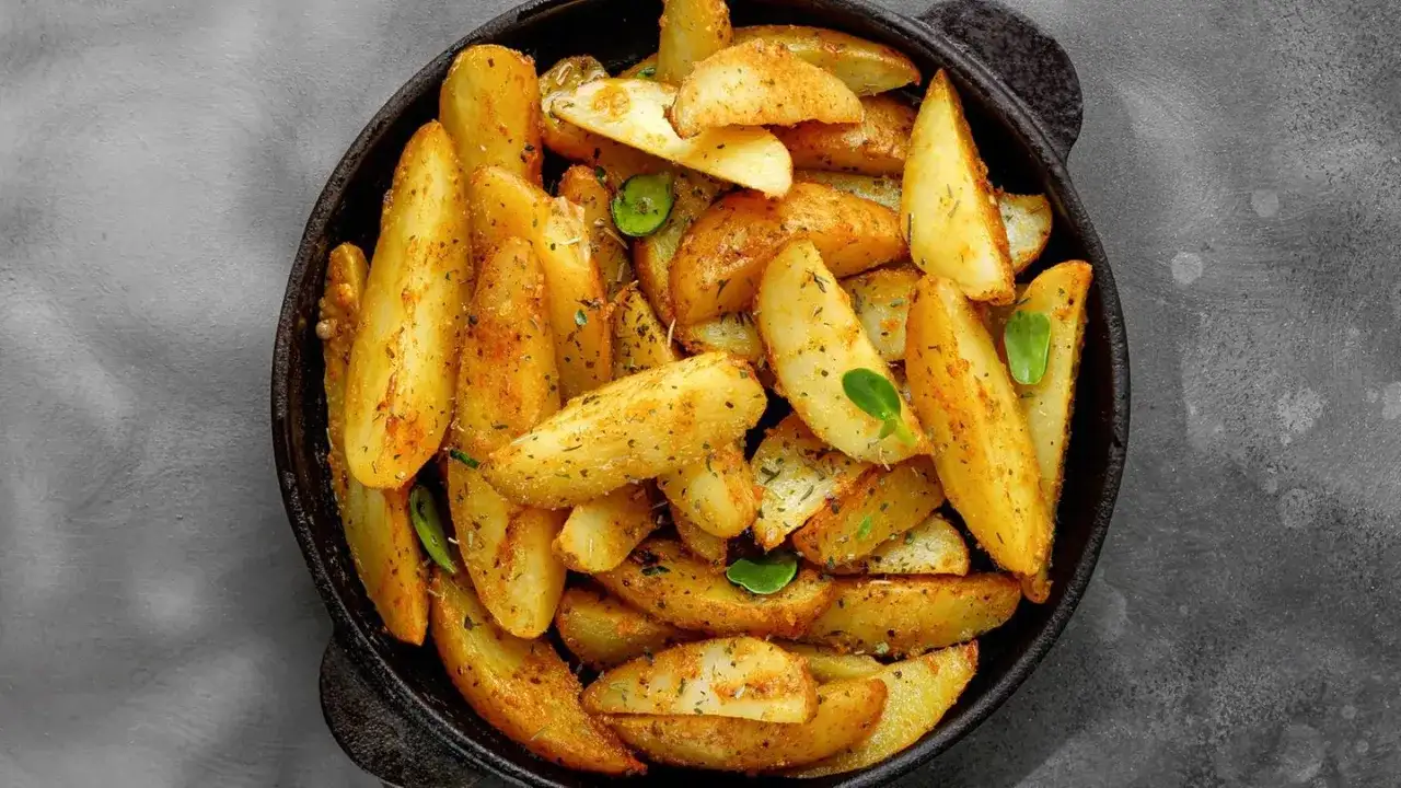 Goldbraune Ofenkartoffeln mit Kräutern und Gewürzen in einer Pfanne. Perfekt für ein einfaches Ofenkartoffeln Rezept.