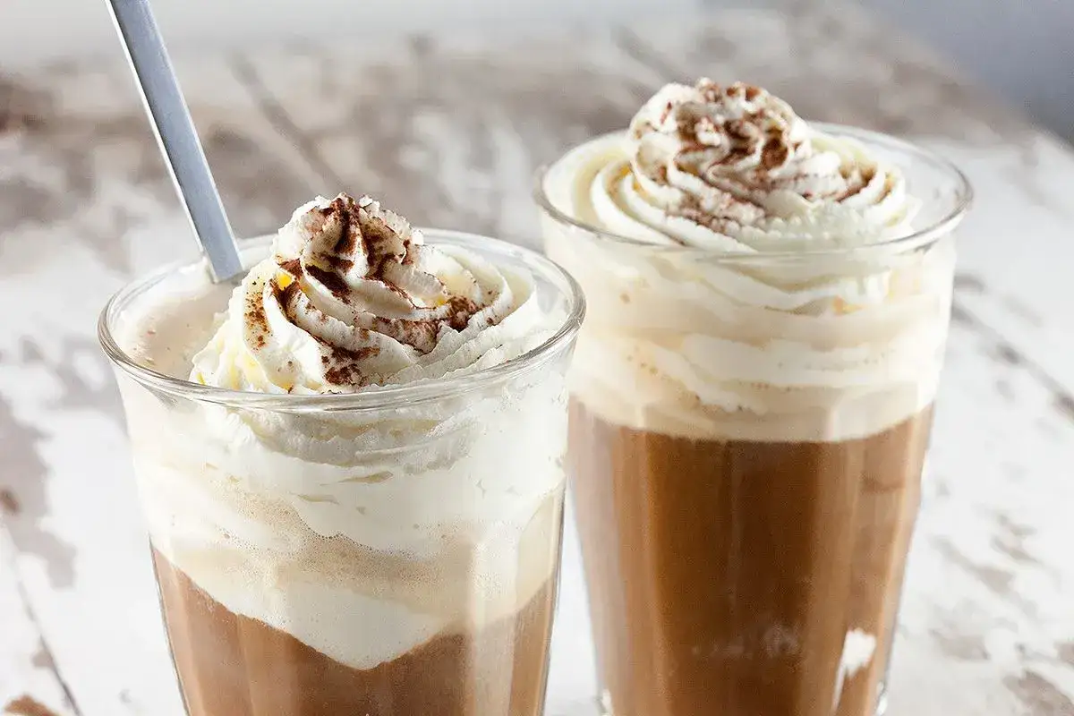 Zwei leckere Eiskaffee-Getränke mit Sahne und Kakaopulver. Perfekt für ein erfrischendes Eiskaffee Rezept.