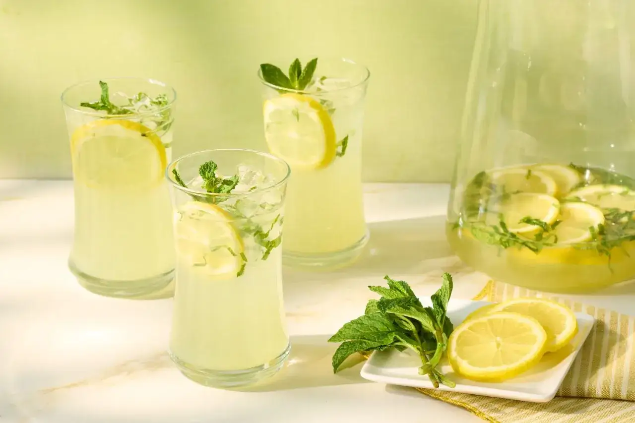 Erfrischende selbstgemachte Limonade mit Zitrone und Minze in Gläsern und Karaffe. Perfekt für heiße Tage!