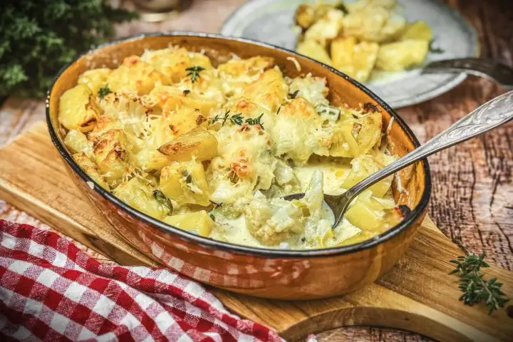 Herzhafter blumenkohl auflauf mit Kartoffeln und Käse überbacken, dampfend in einer Auflaufform.